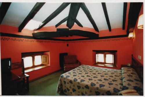 a bedroom with red walls and a bed and two windows at Hotel Posada del Pas in Ontaneda