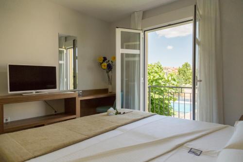 een slaapkamer met een bed, een televisie en een balkon bij Pradaria Asador & Alojamiento in Arcas