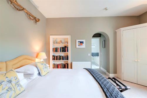 a bedroom with a large white bed and a book shelf at Pentillie Castle and Estate in Saltash