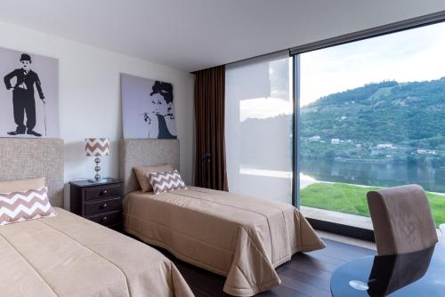 a bedroom with two beds and a large window at Feel Discovery Douro Cherry in Resende