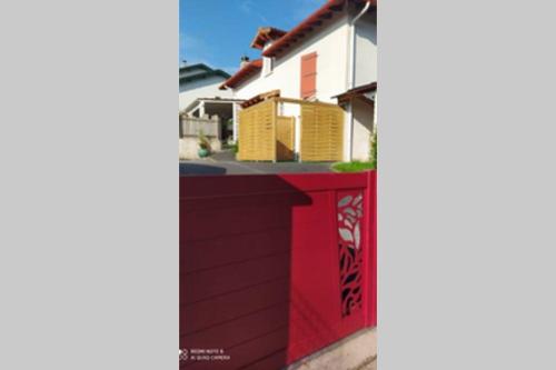 a red fence in front of a house at Appartement tout confort au calme avec jacuzzi in Mouguerre