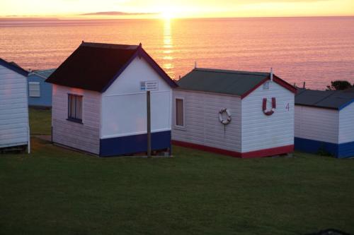a row of beach huts with the ocean in the background at The Royal Clovelly caravan with sea views in Bideford