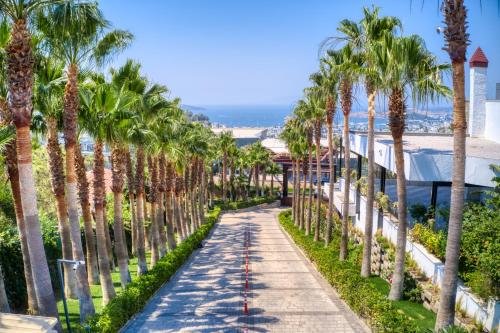a sidewalk lined with palm trees next to the ocean at Hillstone Bodrum Hotel & Spa in Bodrum City