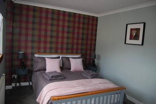 a bedroom with a bed with pink pillows at Creag Mhor Self Catering Holiday Apartment in Aberfoyle