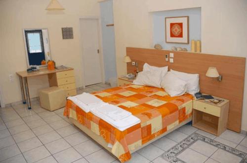 a bedroom with a large bed and a desk at Aggelos Hotel in Agios Andreas