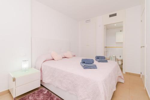 een witte slaapkamer met een bed met handdoeken erop bij Espanatour ELVIRA in Orihuela-Costa