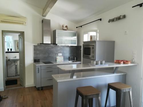 une cuisine équipée d'appareils en acier inoxydable et de tabourets dans l'établissement GITE AVEC SPA JACUZZI au cœur de Provence Côte d'Azur, à Saint Antonin du Var