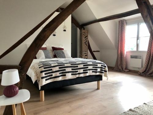 ein Schlafzimmer mit einem schwarzen und weißen Bett im Dachgeschoss in der Unterkunft Le charme et l’original in Ailly-le-Haut-Clocher