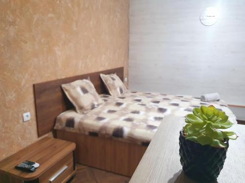 een slaapkamer met een bed en een tafel met een potplant bij Студио Теа 2 in Sliven