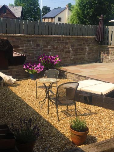 a patio with a table and chairs and flowers at Sound of the River in Talgarth