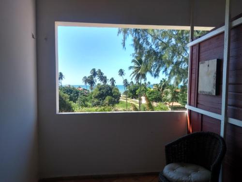 a window in a room with a chair looking out at the ocean at Casa Cohiba in Cumbuco