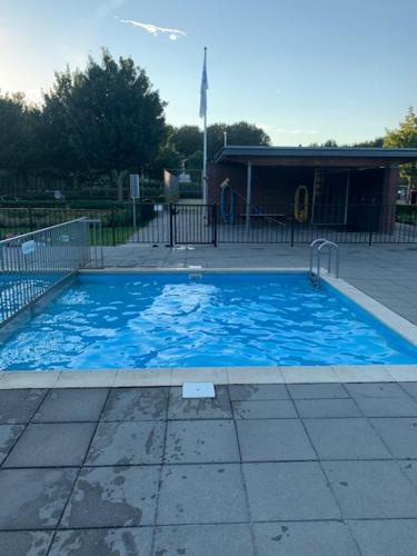 a large blue swimming pool in front of a building at Vakantiehuis Villa Zeewolde in Zeewolde