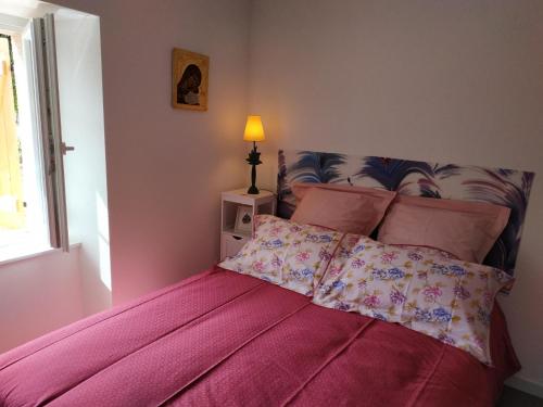 a bed with a pink comforter in a bedroom at Chambres d'Hôtes La Courlande in Saint-Haon-le-Vieux