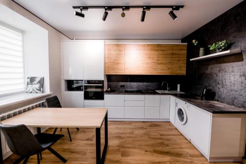 a kitchen with white cabinets and a wooden table at Апартаменти VIP в центрі Чорткова in Chortkiv