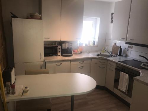 a kitchen with white cabinets and a white table at Chill out 2 in Sulzbach am Main