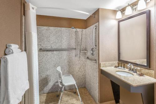 a bathroom with a sink and a shower and a chair at Wingate by Wyndham - St. George in St. George