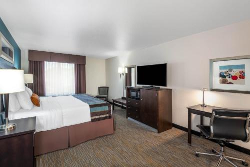 a hotel room with a bed and a desk and a television at Wingate by Wyndham - St. George in St. George