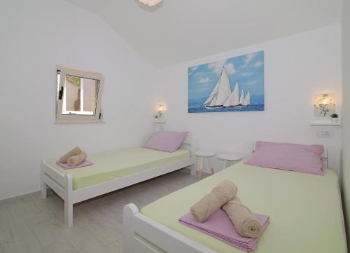 a bedroom with two beds and a sail boat on the wall at Apartments Marija Vukas in Dubrovnik