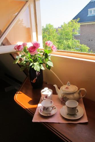 un tavolo con due tazze da tè e un vaso con fiori di Wild Roses ad Amsterdam