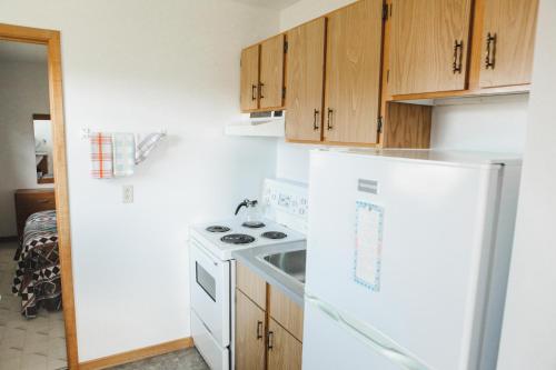 Il comprend une cuisine équipée d'une cuisinière blanche et de placards en bois. dans l'établissement Peck's Housekeeping Cottages, à Louisbourg