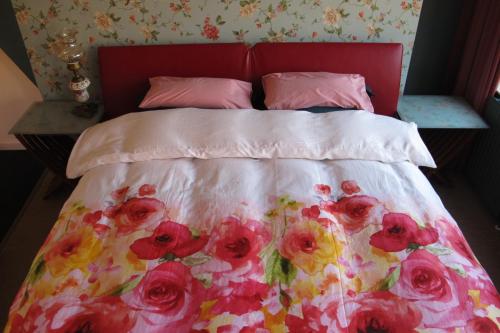 1 cama con colcha rosa con motivos florales y almohadas rosas en Wild Roses, en Ámsterdam