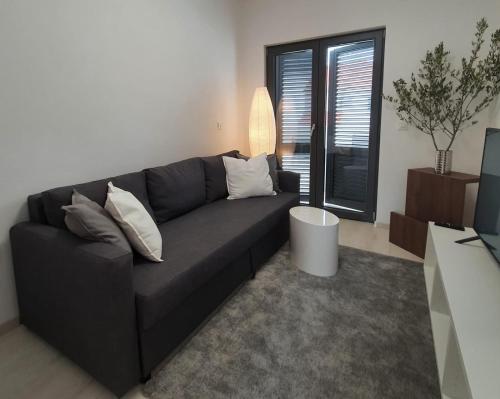 a living room with a black couch and a window at Villa Aquamarine Apartments in Novalja