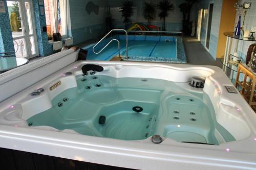 a jacuzzi tub with a pool in the background at Penzión Hellene in Piešťany