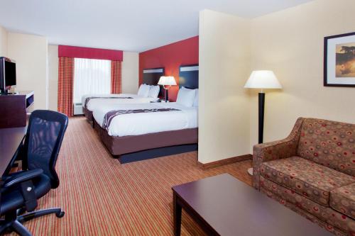 a hotel room with two beds and a couch at La Quinta by Wyndham Warner Robins - Robins AFB in Warner Robins