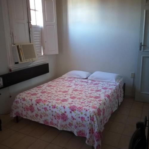 a bedroom with a bed with a floral bedspread and a window at Hotel Central in Recife