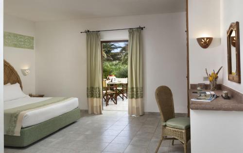 a hotel room with a bed and a desk and a table at Hotel Relax Torreruja Thalasso & Spa in Isola Rossa