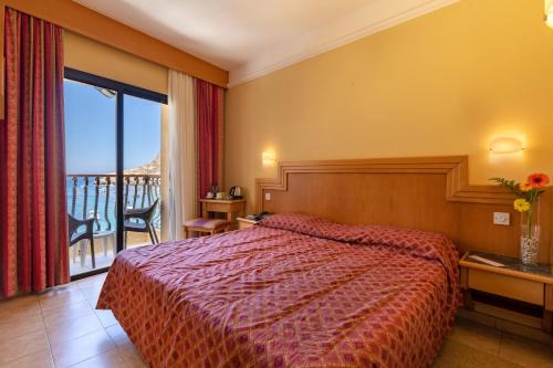 a hotel room with a bed and a balcony at Hotel San Andrea in Xlendi