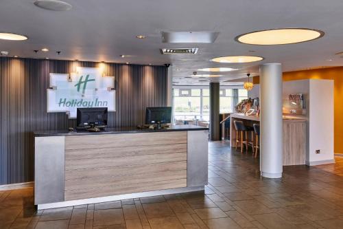 a lobby of a hotel with a reception desk at Holiday Inn Ellesmere Port/Cheshire Oaks by IHG in Ellesmere Port