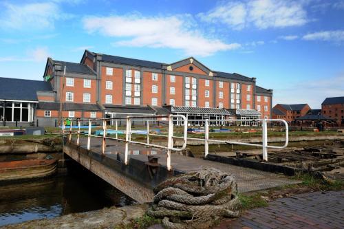 a large red brick building next to a body of water at Holiday Inn Ellesmere Port/Cheshire Oaks by IHG in Ellesmere Port