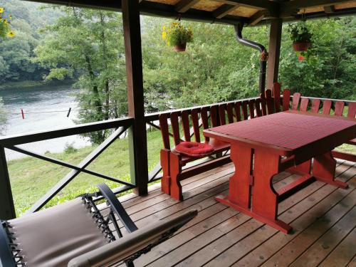 a picnic table and chairs on a porch with a view of a river at Brvnara na obali reke Drine in Beserovina