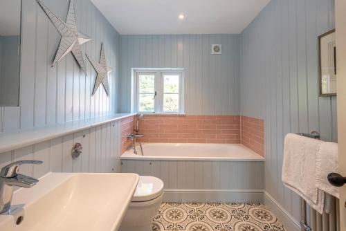 a bathroom with a tub and a toilet and a sink at Owl Cottage in Wighton