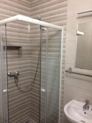 a shower with a glass door next to a sink at Harmónia Panzió in Bogács