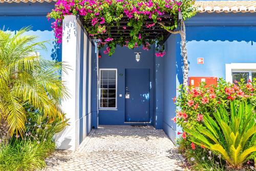 a blue house with flowers in front of it at Aldeia Azul Resort in Lagos