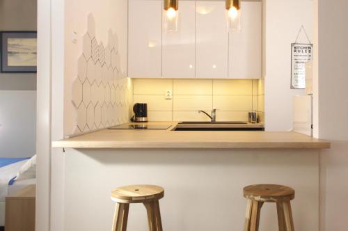 a kitchen with white cabinets and two wooden stools at Apartment Zagreb 213 in Zagreb