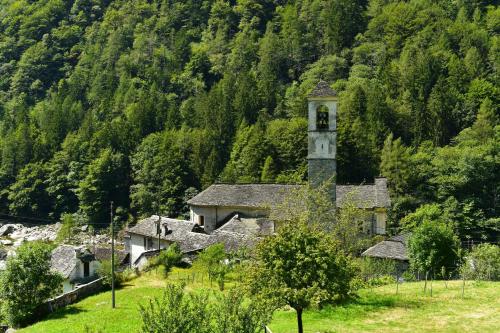 an old building with a clock tower on a hill at Rustico Luchessa Valle Verzasca in Lavertezzo