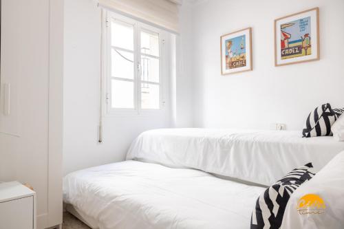 2 Betten in einem Zimmer mit weißen Wänden und einem Fenster in der Unterkunft Casa Genoves by Cadiz Time in Cádiz