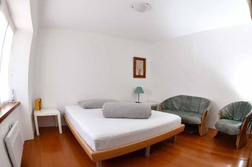 a bedroom with a bed and two chairs at Rustico Luchessa Valle Verzasca in Lavertezzo