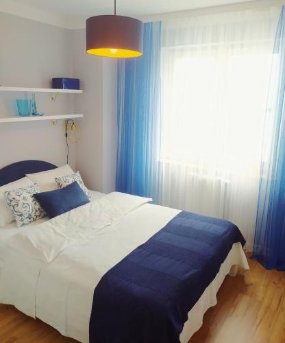 1 dormitorio con 1 cama con cortinas azules y ventana en Apartament Niebieski, en Świnoujście