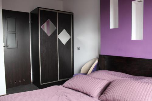 a bedroom with a bed and a purple wall at Willa Marion in Karpacz