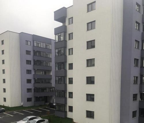 um edifício de apartamentos branco com carros estacionados num parque de estacionamento em Apartment Pitesti em Piteşti