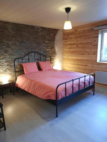 Cette chambre comprend un lit avec des draps roses et un mur en briques. dans l'établissement Al'fagne de boca, à Bertogne