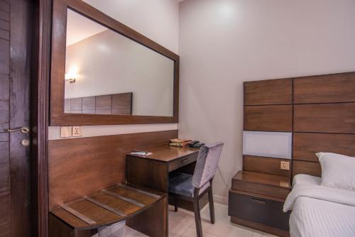 a bedroom with a desk and a mirror next to a bed at Hillside Homes in Karachi