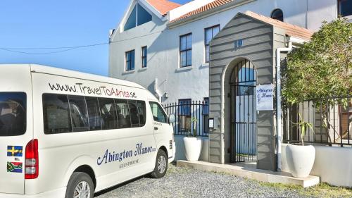 a white bus parked in front of a brick building at Abington Manor Fish Hoek Guesthouse in Fish Hoek