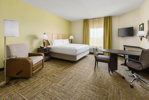 a hotel room with a bed and a desk and chairs at Candlewood Suites - Orlando - Lake Buena Vista by IHG in Orlando