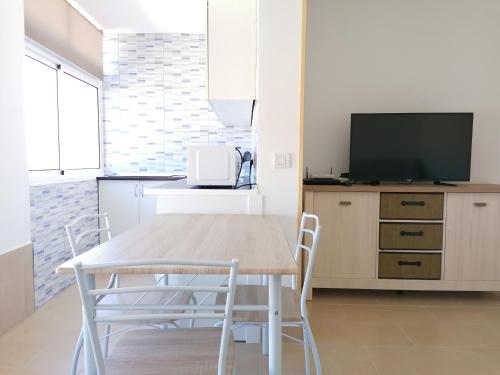コラレホにあるApartamentos lidiaのキッチン(テーブル、椅子、テレビ付)
