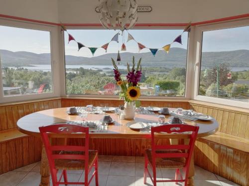 una sala da pranzo con tavolo, sedie e finestre di Grenane Heights a Kenmare